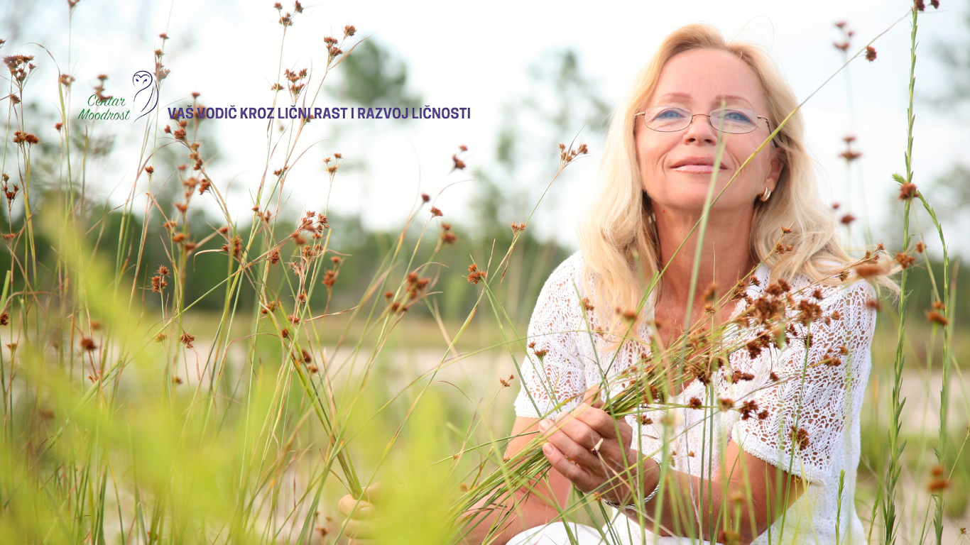 Srećna plava žena s naočarima sedi na livadi.