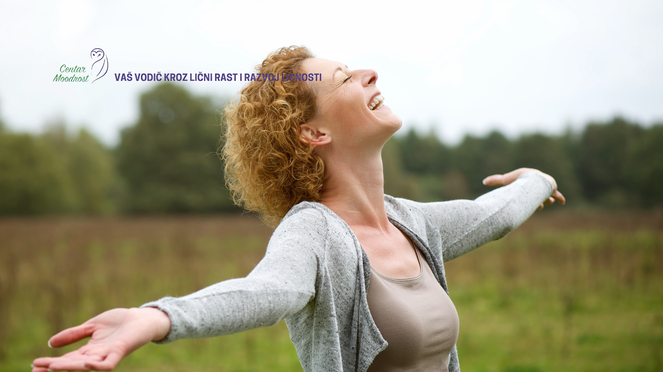 Vesela i srećna žena raširenih ruku uživa u prirodi.